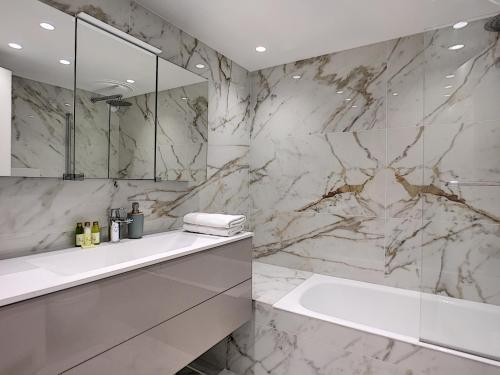 La salle de bains en marbre est pourvue d'un lavabo et d'une baignoire. dans l'établissement Nestor&Jeeves - DIAMOND BAY TERRACE - Central - Close sea, à Nice