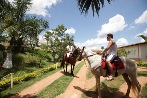 Dois homens cavalgando por uma estrada de terra em Hotel Fazenda Vale Amanhecer em Igarapé