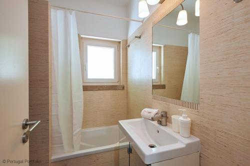 Baño blanco con lavabo y espejo en Central Oasis Apartment, en Cascais