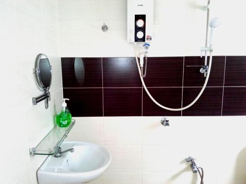 ein Bad mit einer Dusche, einem Waschbecken und einem Spiegel in der Unterkunft Happy Sweet Residence in Malakka