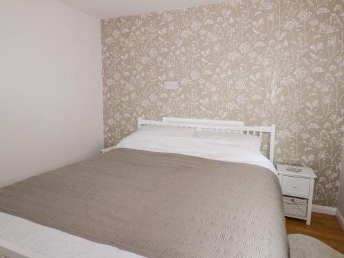 a bedroom with a bed and a wall with floral wallpaper at Thirley Beck Lodge in Scarborough