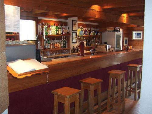 a bar with wooden stools and a counter with a bar at Le Grand Tetras in Saint-Véran