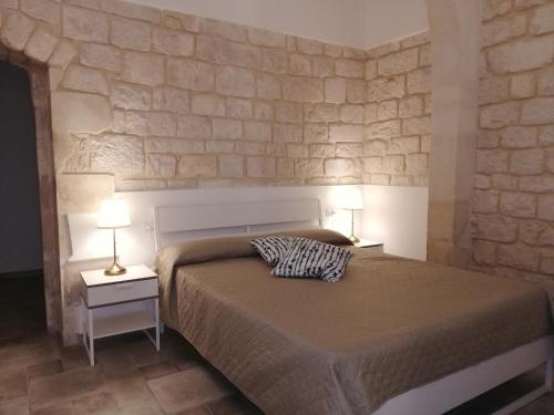 a bedroom with a bed and a stone wall at Triskelion in Scicli