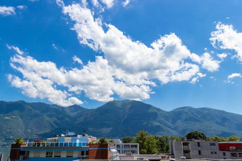 a view of mountains and a blue sky with clouds at H4 Hotel Arcadia Locarno in Locarno