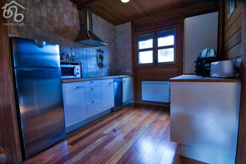 a kitchen with a stainless steel refrigerator and wooden floors at Panoramic Xalet la Molina con Vistas Excelentes in La Molina
