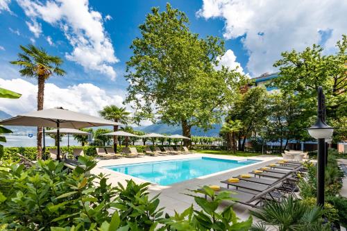 une piscine avec des chaises longues et des parasols dans un hôtel dans l'établissement H4 Hotel Arcadia Locarno, à Locarno