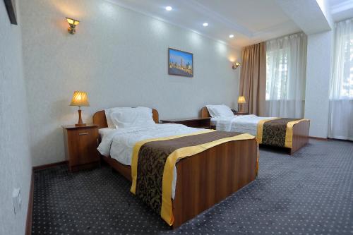 a hotel room with two beds and two lamps at VIARDO Hotel in Tashkent