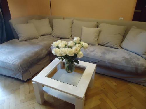 a living room with a couch and a vase of flowers on a table at Apartment Jafa in Tbilisi City