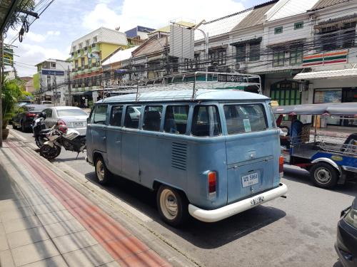 a blue van is driving down a city street at Tepbunthom Hostel in Bangkok