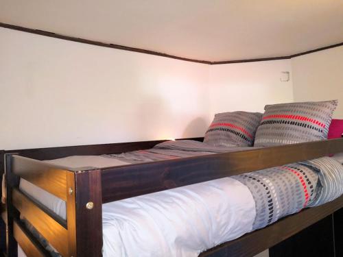 1 cama con marco de madera y almohadas en Mini Studio de 13 m2 avec terrasse 15 mn centre Nimes, en Nimes