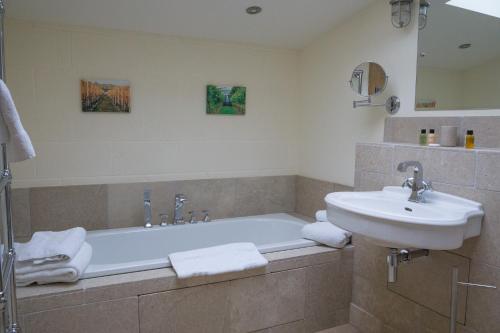 a bathroom with a bath tub and a sink at Vineyard Barn Room in Stroud