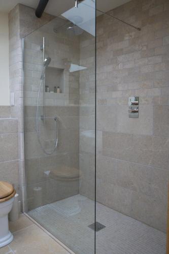 a shower with a glass door in a bathroom at Vineyard Barn Room in Woodchester