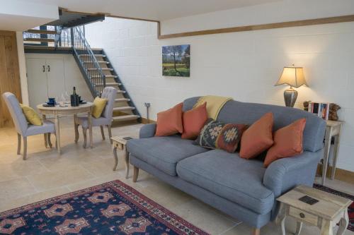 a living room with a blue couch and a table at Vineyard Barn Room in Woodchester