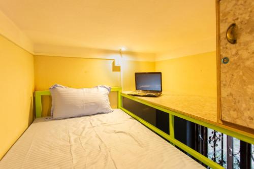 a small room with a bed and a laptop on a desk at Big Tree Hostel in Kathmandu