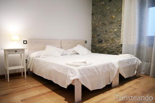 um quarto com uma cama grande e lençóis brancos em Apartamento Llerandi 1C - Ideal para dos personas em San Vicente de la Barquera