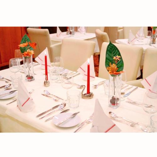 a white table with red candles and napkins on it at Hotel Aragia in Klagenfurt