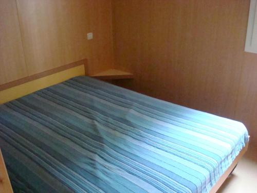 a bedroom with a bed with a blue bedsheet at Village-Chalets Le Rû du Pré in Cravant