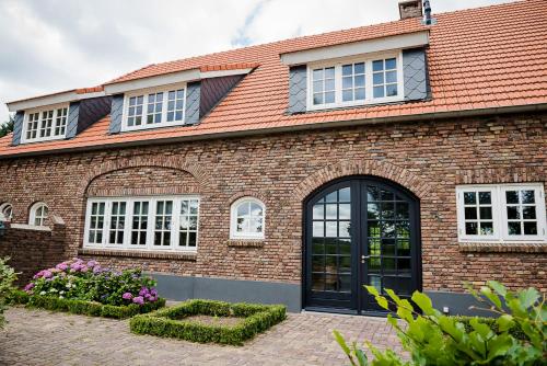 una casa de ladrillo con puertas y ventanas negras en Aan de Molenberg en Broekhuizen