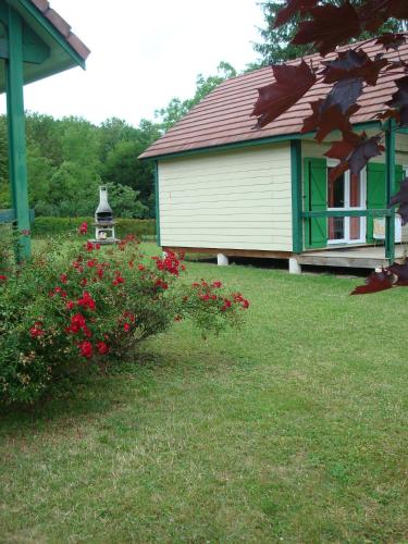 a house with a red roof and a bush with red flowers at Village-Chalets Le Rû du Pré in Cravant