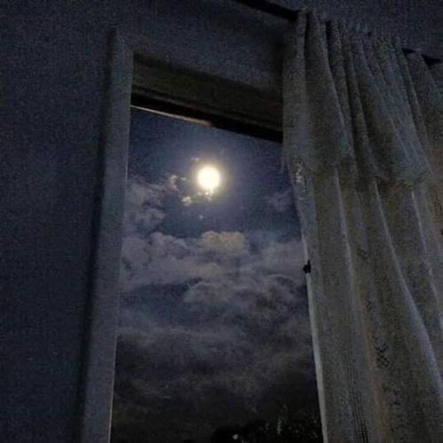 a moon seen through a window with a curtain at Casa Krisdalia in Moyogalpa