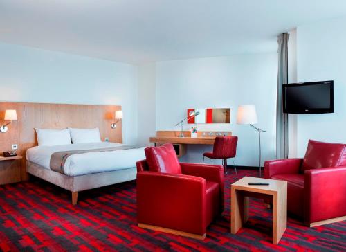 a hotel room with a bed and two red chairs at Park Inn by Radisson Aberdeen in Aberdeen