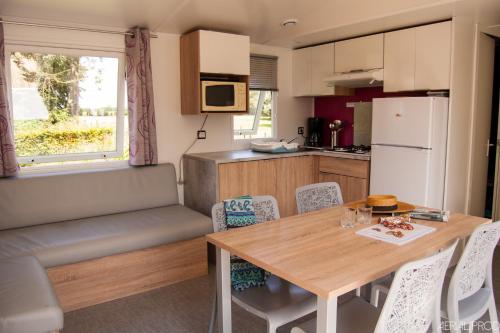 a kitchen and dining room with a table and chairs at Camping la Haie Penée **** in Saint-Quentin-en-Tourmont