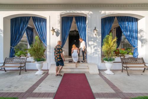 a bride and groom standing on the front porch of a house at El Candil Boutique Hotel in Havana