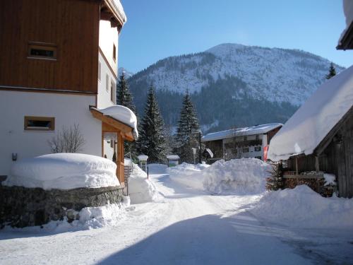 a snow covered street next to a building with a mountain at Haus Brandhofer in Häselgehr