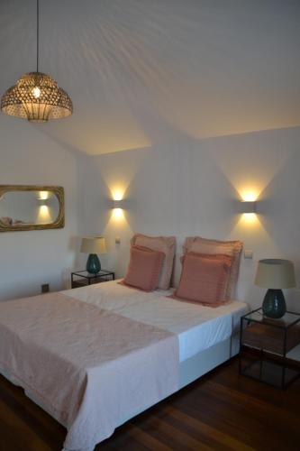 um quarto com uma grande cama branca e 2 candeeiros em Herdade Ribeira de Borba em Vila Viçosa