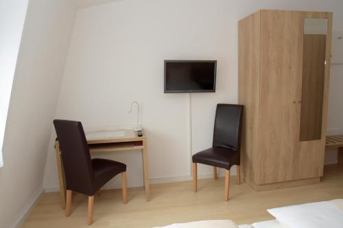 Habitación con 2 sillas, escritorio y TV. en Hotel - Restaurant Baumann en Freiberg am Neckar