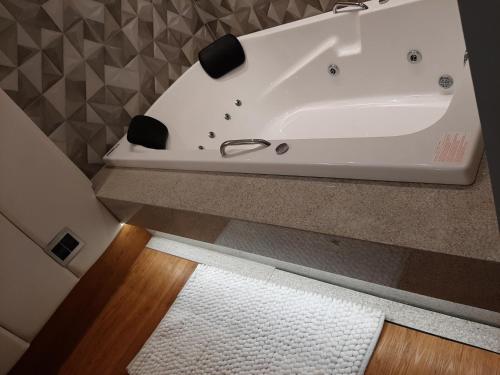a white bath tub in a bathroom with a rug at Pontual Hotel in Bocaiúva
