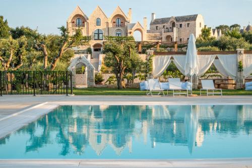 a villa with a swimming pool in front of a house at Ottolire Resort in Locorotondo