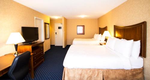 a hotel room with two beds and a flat screen tv at Best Western Plus Suites Downtown Calgary in Calgary