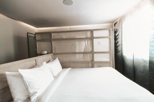 a bedroom with a bed with white pillows and a window at RYO KAN Ciudad de México in Mexico City
