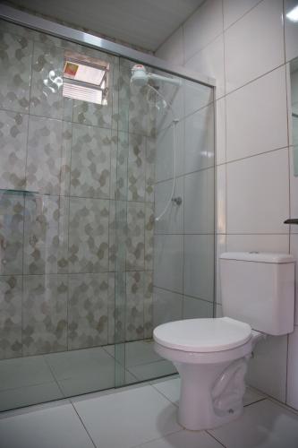 a bathroom with a toilet and a glass shower at Suítes Soure in Soure