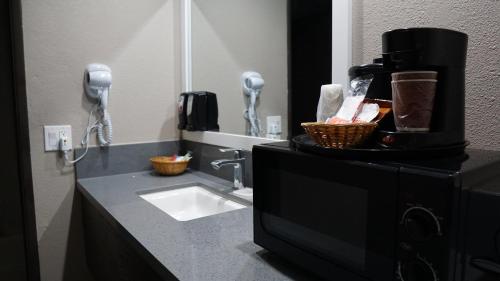 W łazience znajduje się umywalka i telefon. w obiekcie Hawthorne Plaza Inn Near LAX w mieście Hawthorne