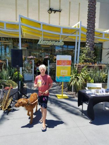 a woman walking a dog in front of a store at The Americana 4 bedroom with spa and bikes, seps to the beach in Huntington Beach