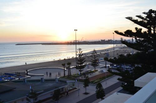 a view of a beach and the ocean at sunset at Hotel Cote ocean Mogador in Essaouira