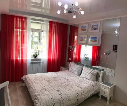 a bedroom with red curtains and a bed and a window at Apartment Studio PARIS 51 in Irpin'