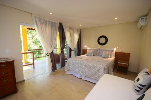 1 dormitorio con 1 cama y balcón en Quintas do Arraial Guest House, en Arraial d'Ajuda