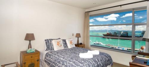 a bedroom with a bed and a large window at Penthouse 39 in Nelson