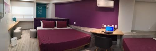 a purple room with a bed and a laptop on a desk at Hotel Bonn in Mexico City