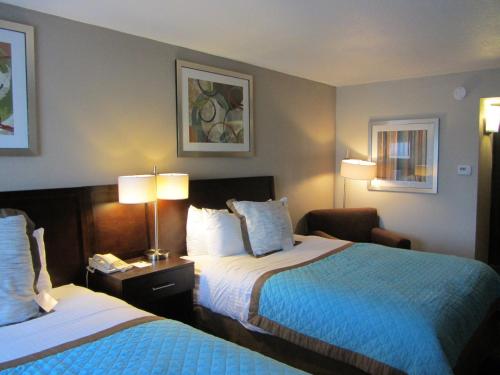 a hotel room with two beds and a chair at Wyndham Garden Midland in Midland