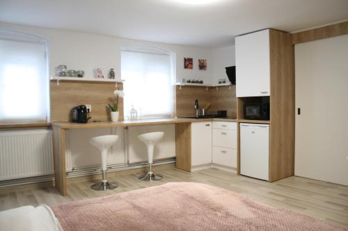 a kitchen with white cabinets and a counter with stools at Apartment BIANCA in Braşov