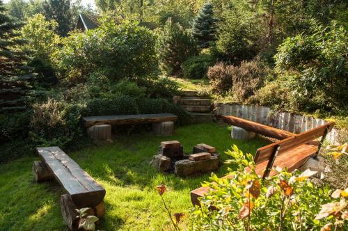 a garden with benches and logs in the grass at Pension Král in Jablonec nad Nisou