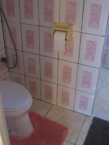 a bathroom with a toilet and a pink rug at Cosy home for short stay or a weekend getaway in Paramaribo