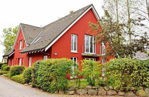 uma casa vermelha com um telhado preto em Ferienwohnung Moewennest mit Terra em Middelhagen