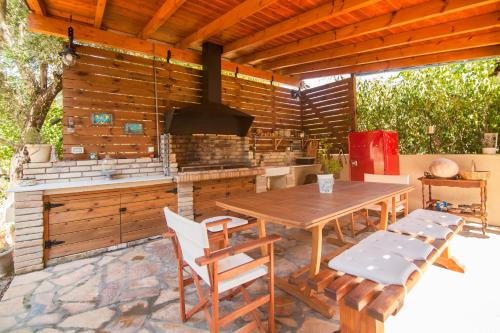 una cocina al aire libre con mesa de madera y sillas en Villa Magia, en Ýpsos