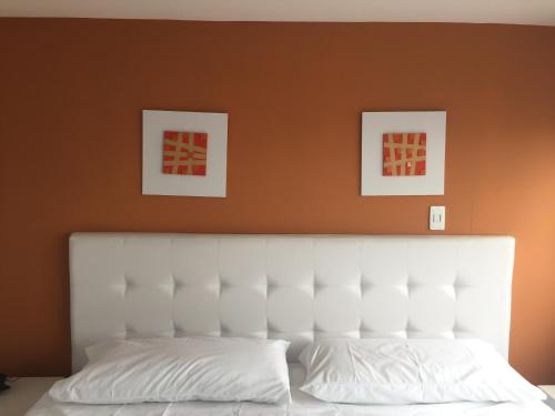 フサガスガにあるHotel Garden City Boutiqueの白いベッド1台、壁に2枚の写真が飾られたベッドルーム1室