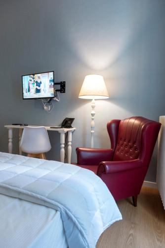 a bedroom with a bed and a chair and a television at Boutique Hotel Palazzo Corso Umberto in Boiano